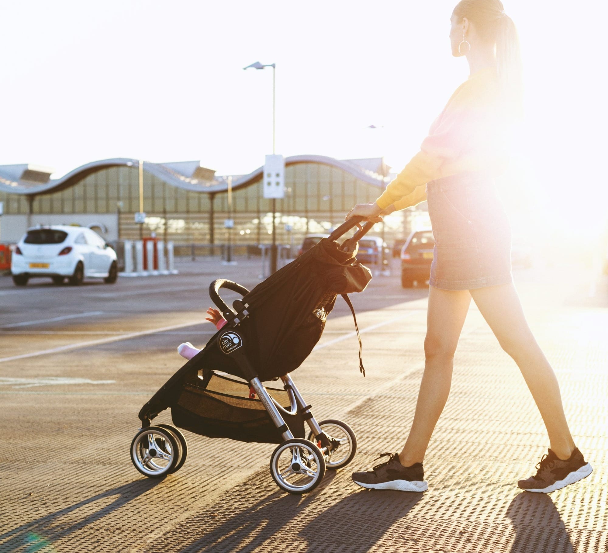 woman pushing baby's stroller on parking area
